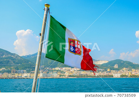 Civil ensign of Italy. National Flag on the background of the sea and mountains 70738509