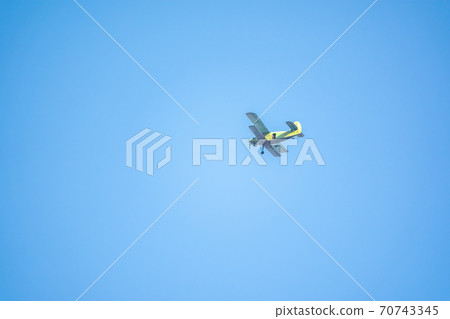Retro green biplane plane in the blue sky Retro green biplane plane in the blue sky 70743345