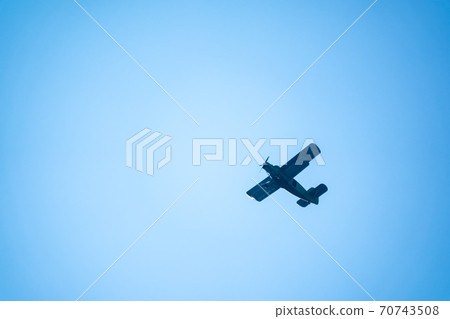 Retro green biplane plane in the blue sky Retro green biplane plane in the blue sky 70743508