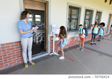 Girl sanitizing her hands at school 70748424
