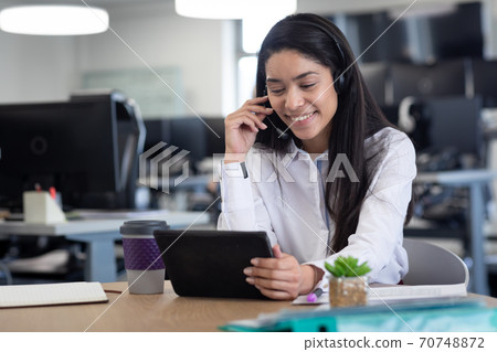 Businesswoman wearing headset using digital tablet at modern office 70748872