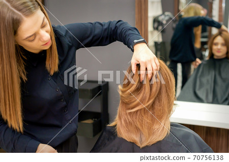 Hairdresser checks hairstyle of woman Hairdresser checks hairstyle of woman 70756138