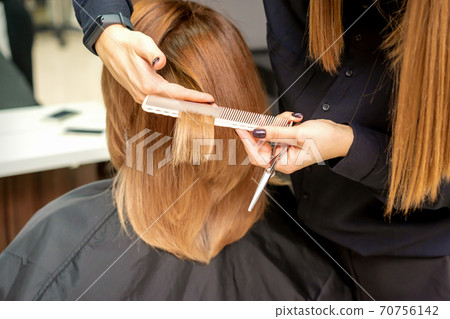 Hairdresser cuts hair to young woman Hairdresser cuts hair to young woman 70756142