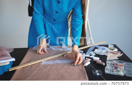 hands laying out sewing accessories on a piece of linen fabric 70757973