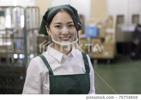 A female employee looking at the camera with a mouse shield in the backyard of a supermarket A female employee looking at the camera with a mouse shield in the backyard of a supermarket 70758608