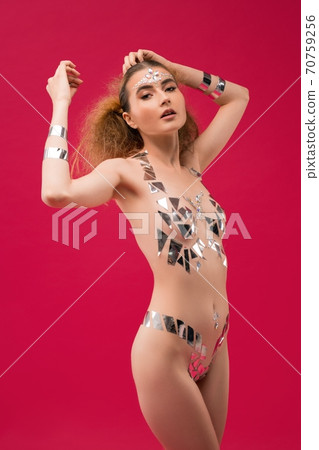 Slim woman with metallic stickers on body look at camera 70759256