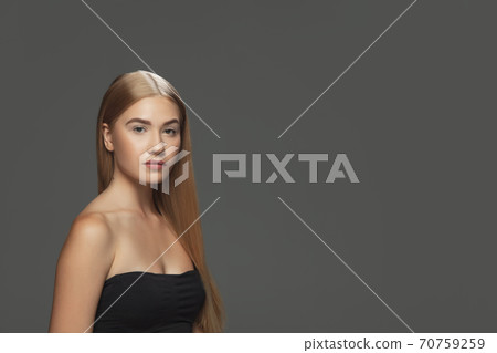 Beautiful model with long smooth, flying blonde hair isolated on dark studio background. 70759259