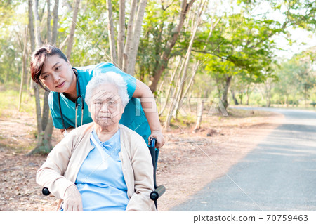 Doctor help and care Asian senior or elderly old lady woman patient sitting on wheelchair at park in nursing hospital ward 70759463