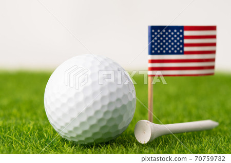Golf ball with USA flag and tee on green lawn or grass is most popular sport in the world. Golf ball with USA flag and tee on green lawn or grass is most popular sport in the world. 70759782