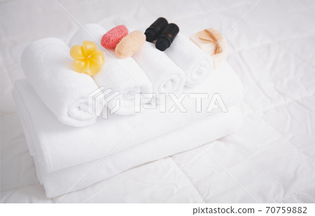 Spa object with  white towels,organic soap,luffa scrub, and plumerai flower candle on clean white bedding. 70759882