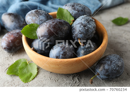 Napkin and bowl with plums on gray background Napkin and bowl with plums on gray background 70760234