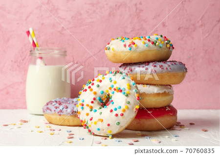 Milk and tasty donuts against pink background 70760835