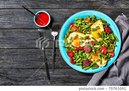 Green beans fried eggs and chorizo on a blue plate 70761091