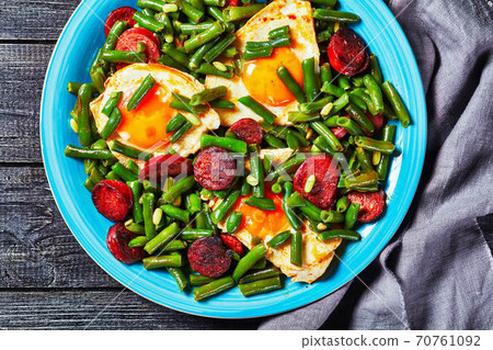 Green beans fried eggs and chorizo on a blue plate 70761092