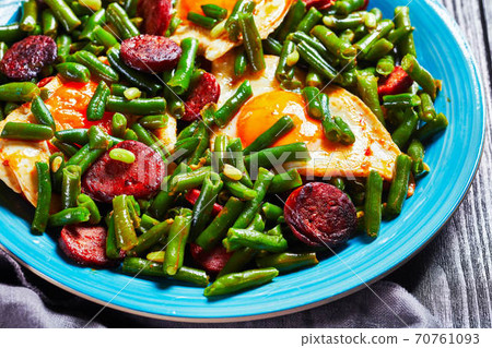 Green beans fried eggs and chorizo on a blue plate 70761093