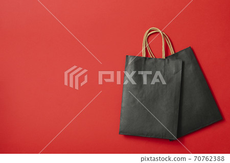 Black paper bags on red background, space for text Black paper bags on red background, space for text 70762388
