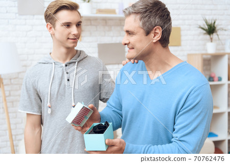 Dad opens the box and smiles at his son. 70762476