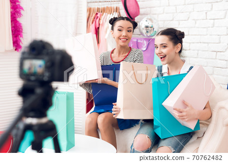 Two fashion blogger girls hold up bags. Two fashion blogger girls hold up bags. 70762482