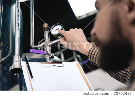 Bearded brewery worker takes readings. 70762485