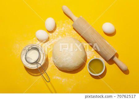 Concept for baking with dough on yellow background 70762517