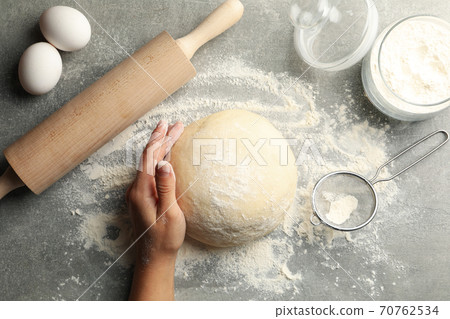 Female hand hold dough on gray background with ingredients for baking Female hand hold dough on gray background with ingredients for baking 70762534