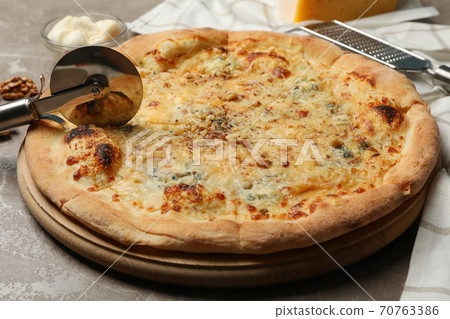 Pizza cutter and cheese pizza, close up 70763386