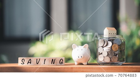 Saving money concepts with coins,house,wood cubics and piggy bank model on nature green grass background Saving money concepts with coins,house,wood cubics and piggy bank model on nature green grass background 70764883