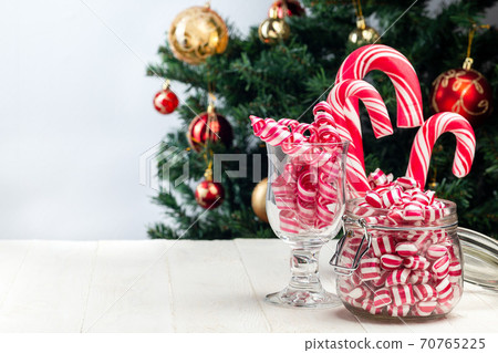 Different kinds of Christmas candy in glass jars, Christmas tree on background, copy space Different kinds of Christmas candy in glass jars, Christmas tree on background, copy space 70765225