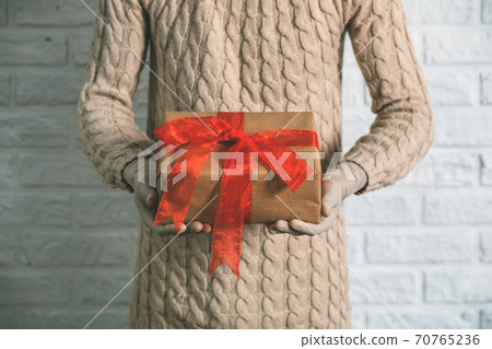 Girl in rubber gloves is holding a gift. Warm knitted sweater, the concept of holidays during the coronavirus pandemic. Girl in rubber gloves is holding a gift. Warm knitted sweater, the concept of holidays during the coronavirus pandemic. 70765236