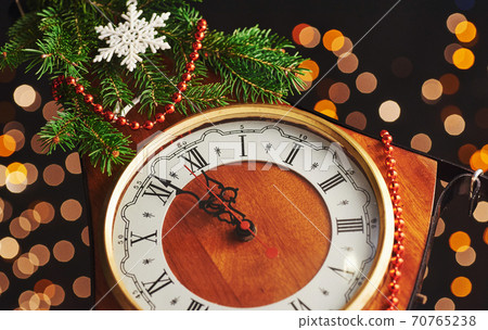 Happy New Year at midnight 2018, Old wooden clock with holiday lights and fir branches Happy New Year at midnight 2018, Old wooden clock with holiday lights and fir branches 70765238
