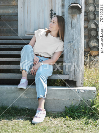 caucasian woman sitting on the stairs of wooden house.  70765358