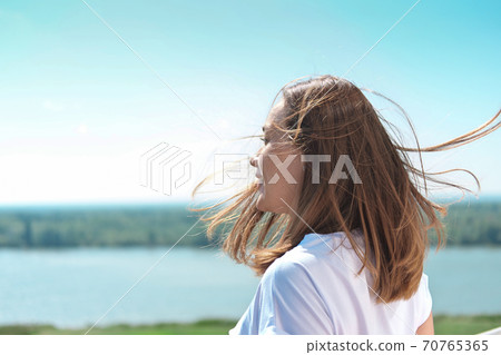 beautiful woman with hair blown by wind looking at landscape beautiful woman with hair blown by wind looking at landscape 70765365