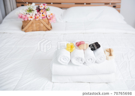 Spa wellness concept with white towels,candle,milk soap,beautiful frangipani  flowers in bamboo wooden basket  on modern white bedroom 70765698