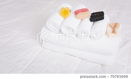 Spa object with  white towels,organic soap,luffa scrub, and plumerai flower candle on clean white bedding. 70765699