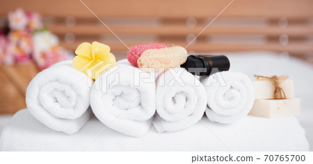 Spa wellness concept with white towels,candle,milk soap,beautiful frangipani  flowers in bamboo wooden basket  on modern white bedroom 70765700