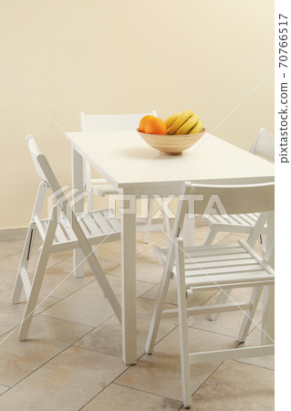White table with fruits and folding chairs in kitchen room 70766517