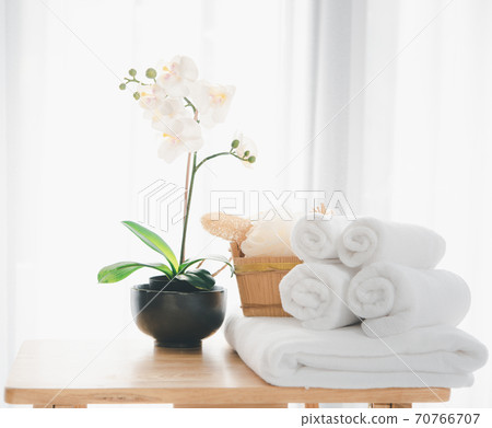 Spa products with white towels,soap,luffa scrub,comb and beautiful orchid flower in clean white room 70766707