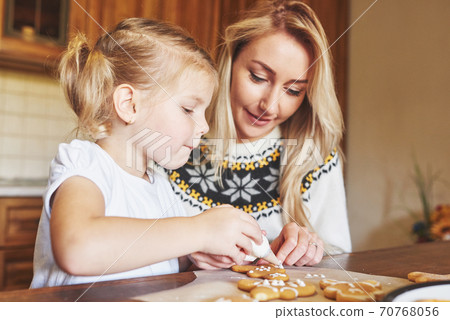 Mom and daughter decorate the Christmas cookie with white sugar Mom and daughter decorate the Christmas cookie with white sugar 70768056