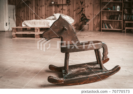 Antique wooden toy horse on the floor of spacious bedroom. Happy childhood memories concept Antique wooden toy horse on the floor of spacious bedroom. Happy childhood memories concept 70770573