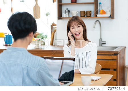 一位與智能手機上的遠程辦公丈夫交談的妻子 70770844