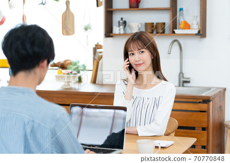 一位與智能手機上的遠程辦公丈夫交談的妻子 70770848