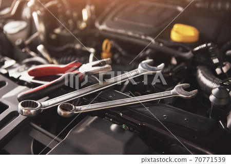 Mechanic hand checking and fixing a broken car in car service garage 70771539