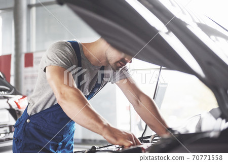 Picture showing muscular car service worker repairing vehicle 70771558