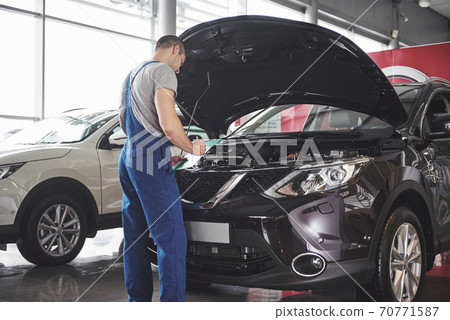 Portrait of a mechanic at work in his garage - car service, repair, maintenance and people concept Portrait of a mechanic at work in his garage - car service, repair, maintenance and people concept 70771587