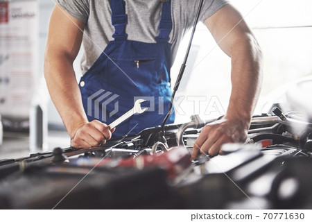 Picture showing muscular car service worker repairing vehicle Picture showing muscular car service worker repairing vehicle 70771630