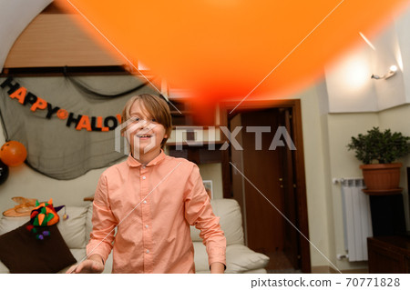 a boy is having fun and playing with orange and black Halloween baloons a boy is having fun and playing with orange and black Halloween baloons 70771828