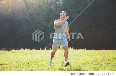 Fitness man athlete jogging in the nature during sunset. Person running working out living an active lifestyle training cardio in summer in sportswear and shoes. Fitness man athlete jogging in the nature during sunset. Person running working out living an active lifestyle training cardio in summer in sportswear and shoes. 70772172