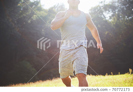Fitness man athlete jogging in the nature during sunset. Person running working out living an active lifestyle training cardio in summer in sportswear and shoes. Fitness man athlete jogging in the nature during sunset. Person running working out living an active lifestyle training cardio in summer in sportswear and shoes. 70772173