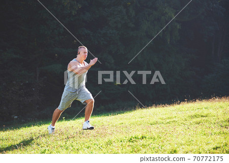 Fitness man athlete jogging in the nature during sunset. Person running working out living an active lifestyle training cardio in summer in sportswear and shoes. Fitness man athlete jogging in the nature during sunset. Person running working out living an active lifestyle training cardio in summer in sportswear and shoes. 70772175