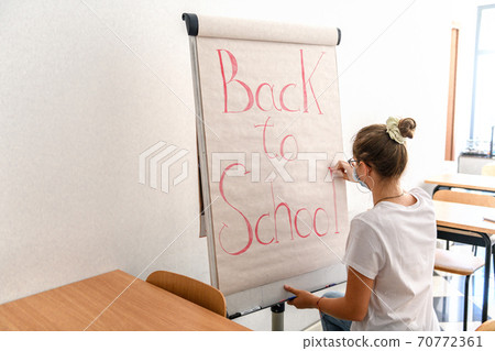 Girl writing back to school on whiteboard wearing Girl writing back to school on whiteboard wearing 70772361